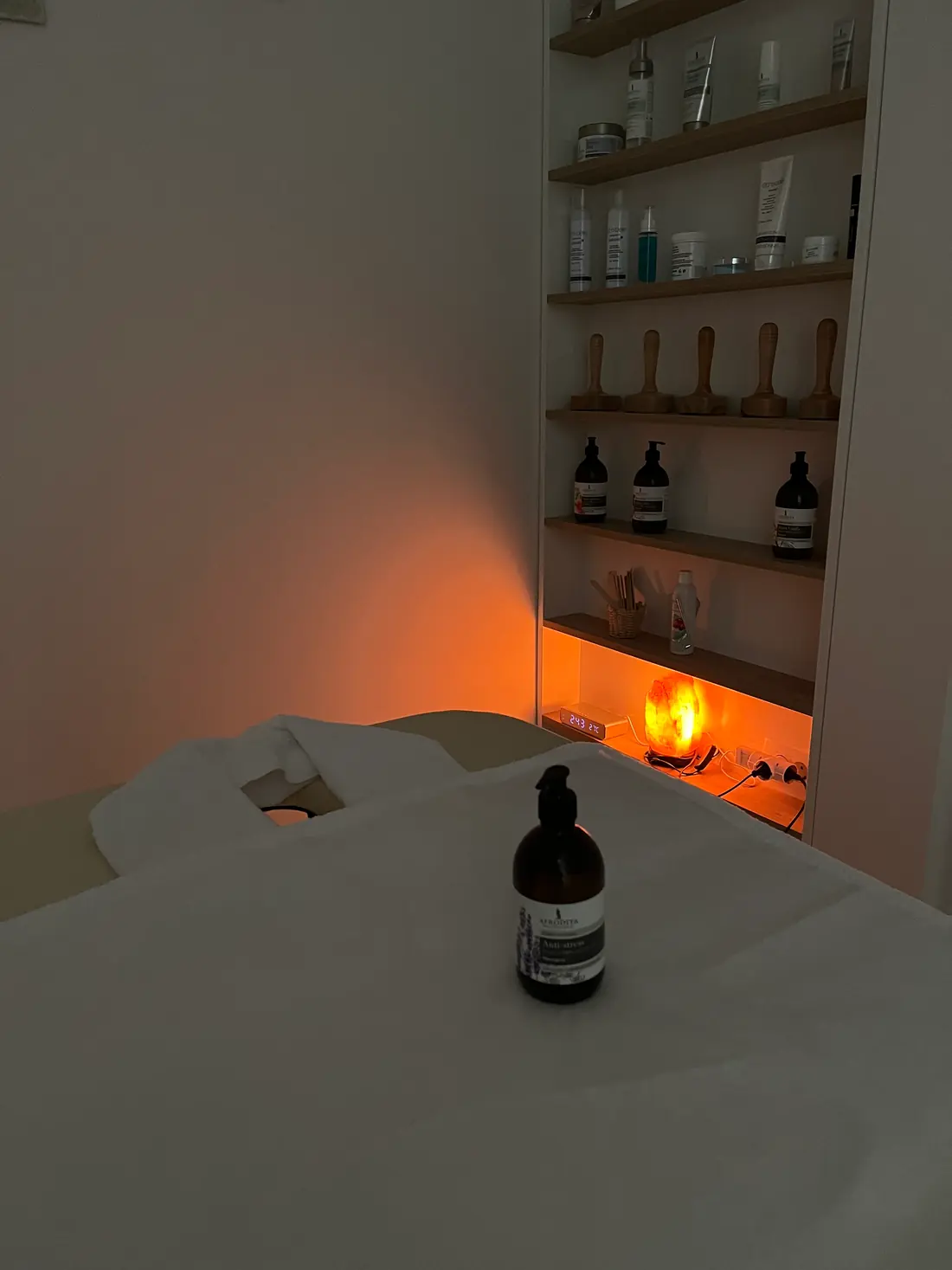 Masažna miza in police z naravno kozmetiko v toplem soju solne lučke
